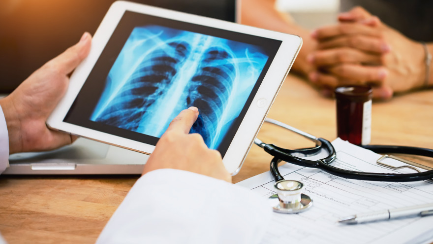 Doctor explaining results of lung check up from x-ray scan chest on digital tablet screen to patient